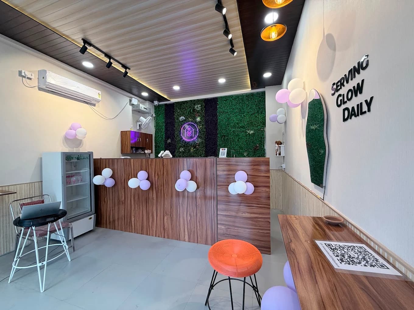 The café interior: walnut counter, moss wall with the neon logo, and pendant lighting